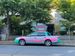The most nineties car you have ever seen, parked on a street in Seattle, Washington. It is a Subaru, Baja — a car with a truck bed. The car is painted teal, pink, grey, red, and yellow. It is apparently a delivery car for a restaurant called Un Bien Caribbean and Latin Food.